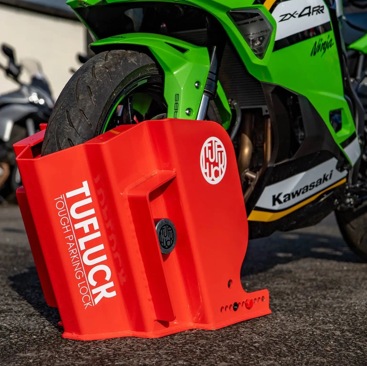 Red TUFLUCK parking lock in front of a green Kawasaki motorcycle